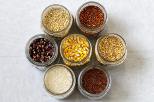 Three rows of different types of grains are in jars. 