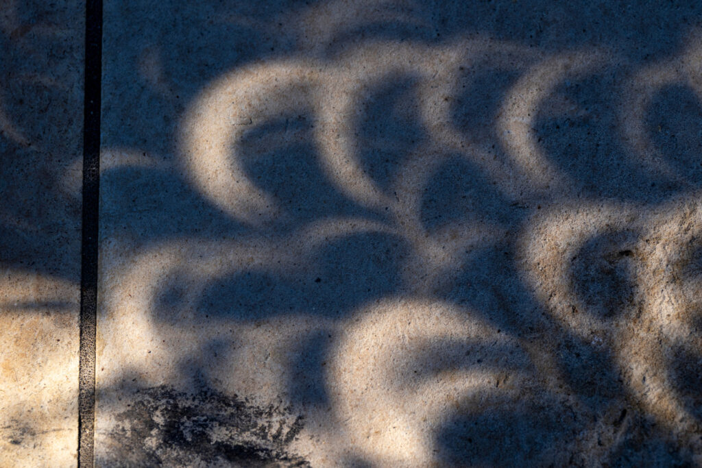 Shadows from the eclipse in 2023 cast along the sidewalk. 