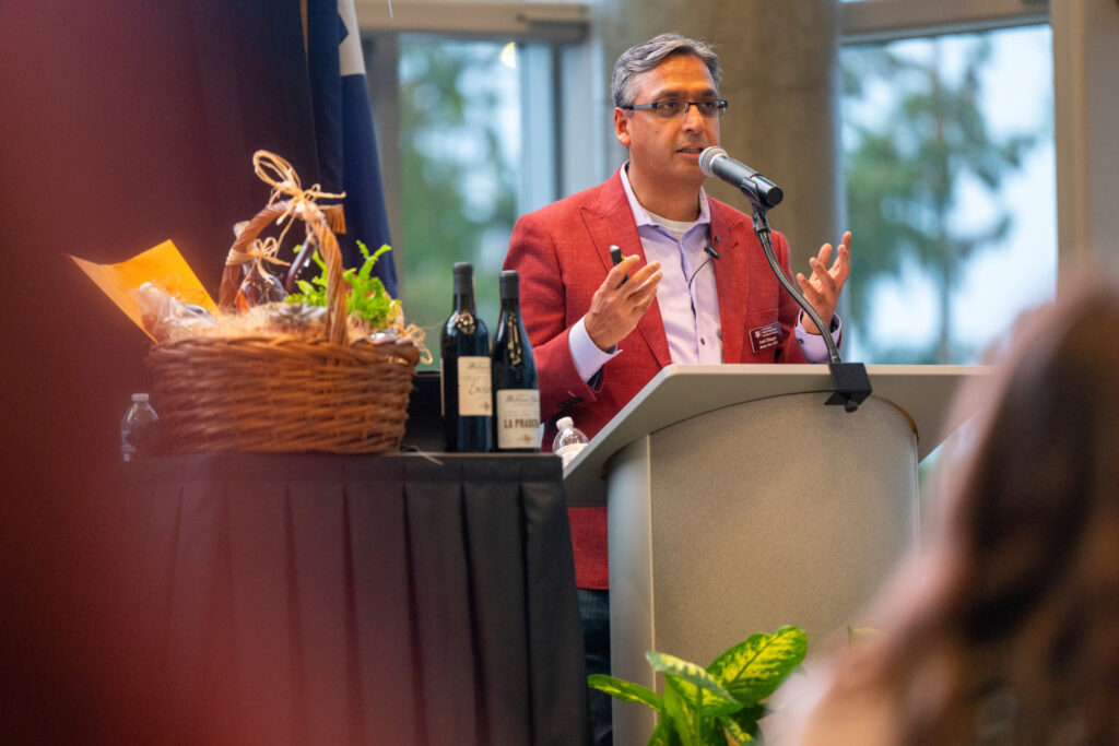 Amit Dhingra, Ph.D., head of the Department of Horticultural Sciences, standing at a podium. He is wearing a red jacket 