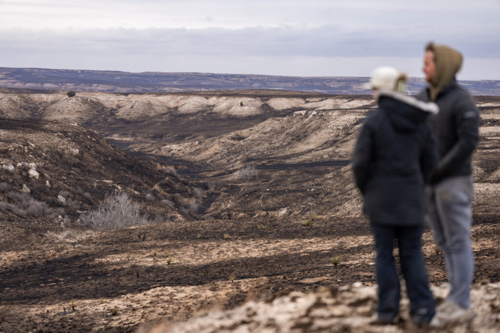 Mental health struggles can be experienced by ranchers such as this couple that stands on black and tan burned pasture land. 