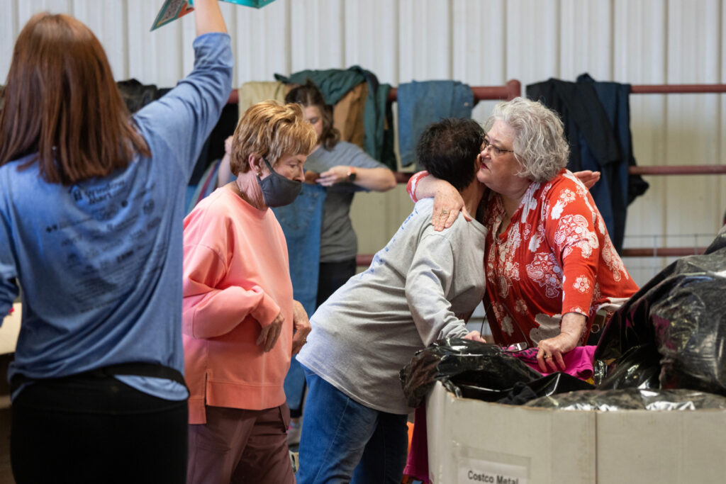women hug as they address the donations arriving for human relief after the wildfires