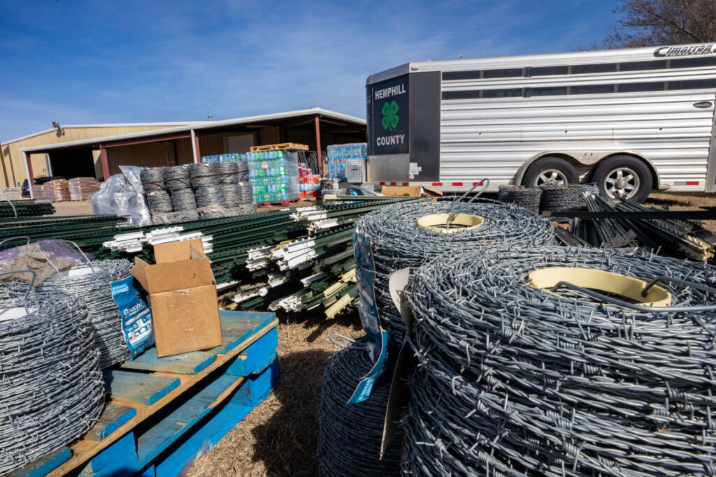 Fencing supplies are stacked at an animal supply point, including coils of barbed wire
