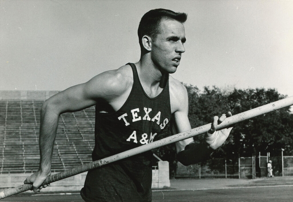 A black and white photo of a man wearing a Texas A&M jersey and pole vaulting