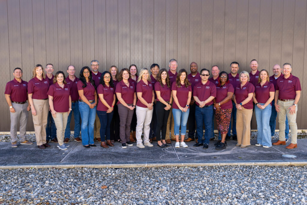 A groip photo of LEAD AgriLife members standing outside a building. They wear matching maroon shirts.