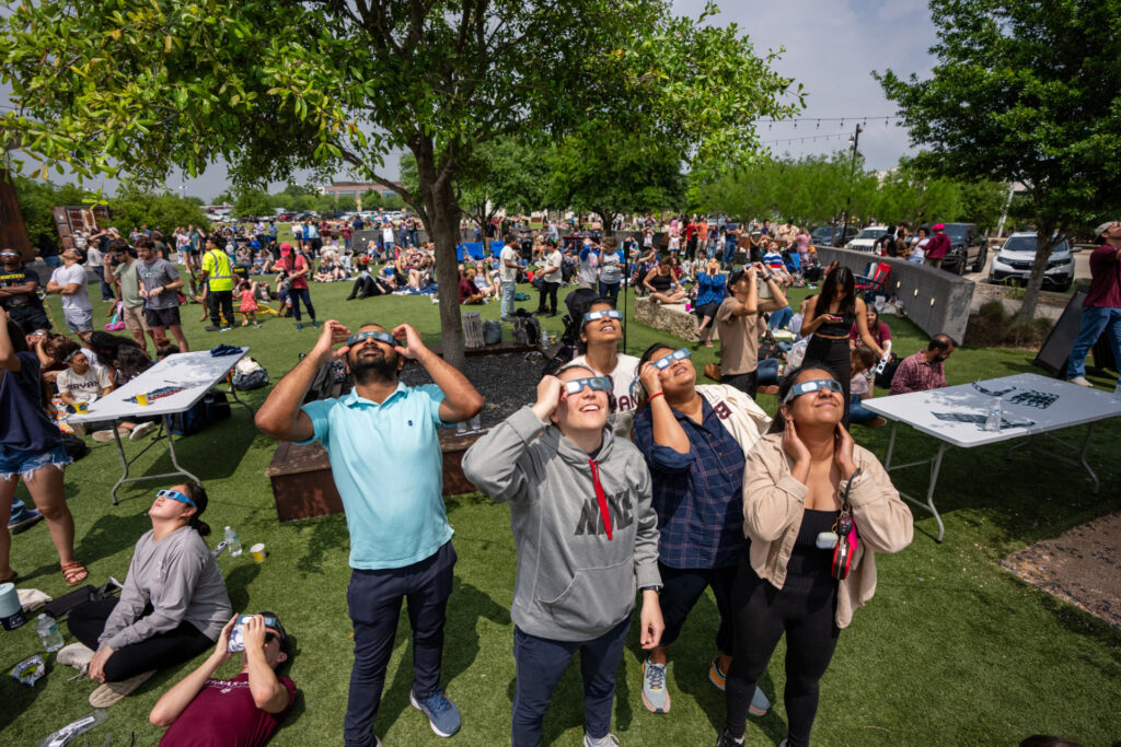 People wearing solar eclipse glasses looking up at the sky.