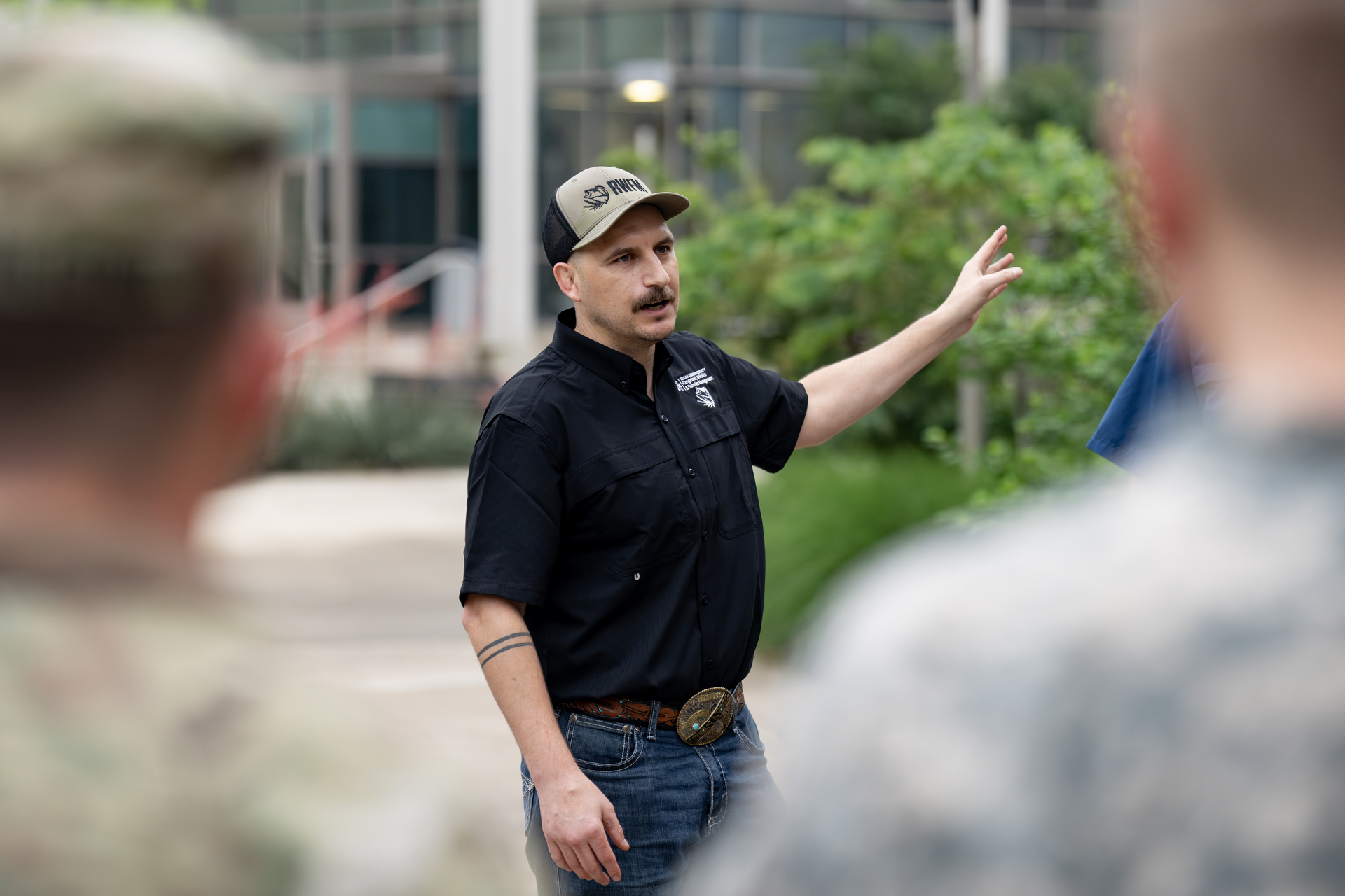 A man (Ty Werdel, Ph.D., assistant professor in the Texas A&M University Department of Rangeland, Wildlife and Fisheries Management) explains squirrel trapping procedures to students