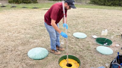 A man is testing a septic system with a long pole.
