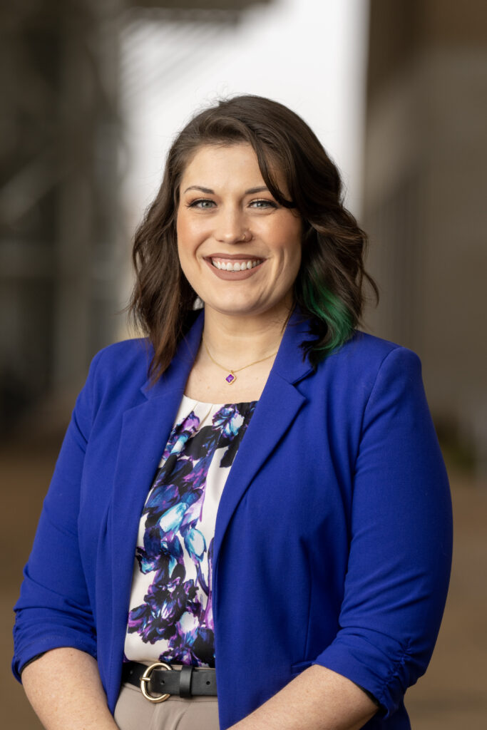 Director of advising for the College of Agriculture and Life Sciences Jennifer Rhinesmith-Carranza, Ph.D., stands in a blue blazer and a flower top.