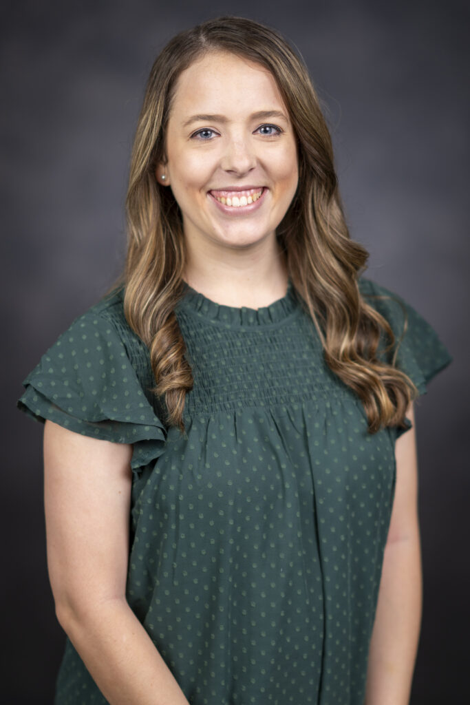 Callan Gearner wears a green blouse while posing for a headshot in front of a grey background. Gearner is an advisor for the College of Agriculture and Life Sciences. 