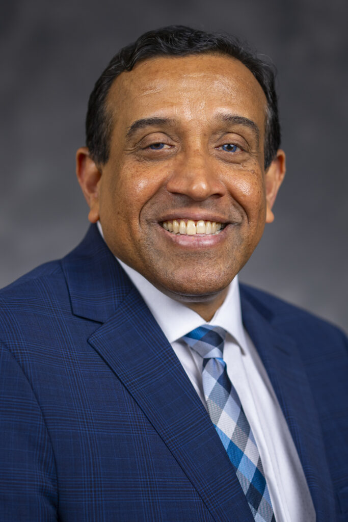 Head and shoulder photo of Dr. Pillai wearing navy blue suit 