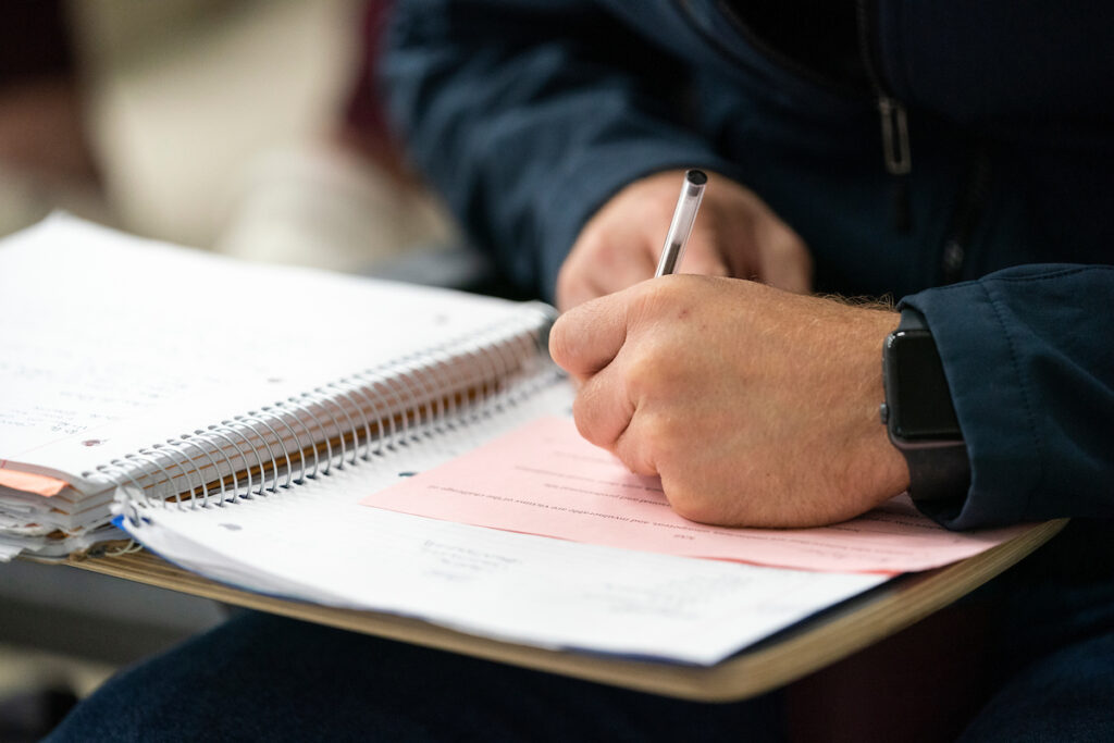 A person is signing papers on a desk. The OneOp webinar on June 26 will explore special needs trusts and alternative accounts. 