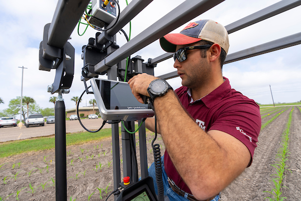 A man in a hat and sunglasses calibrates equipment in a field