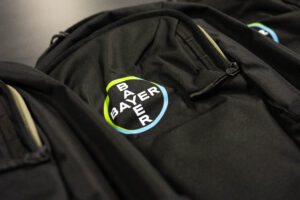 Black backpack with the blue and green Bayer company logo.