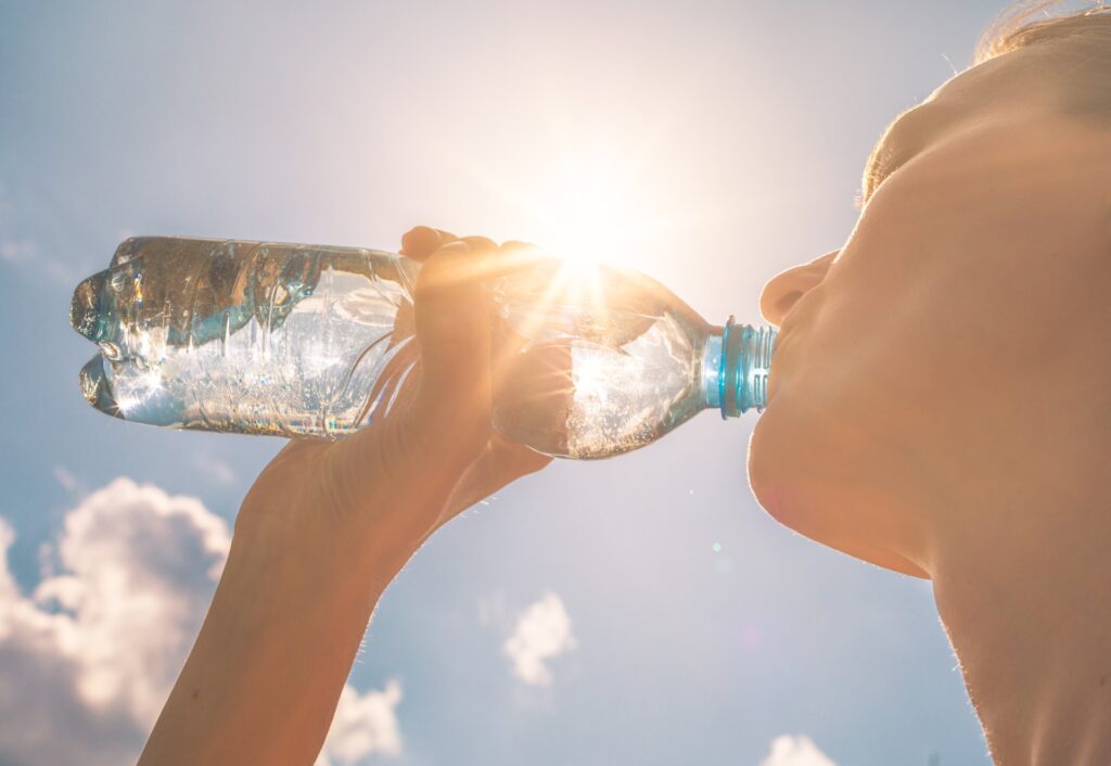 Woman drinking from water bottle during a hot day 