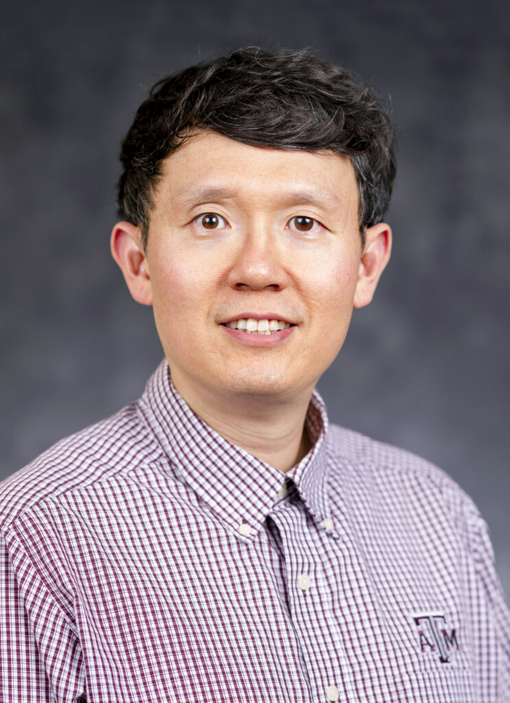 Head and shoulder picture of a man, Seockmo Ku, Ph.D. He is wearing a maroon and white checked shirt with the Texas A&M logo on it
