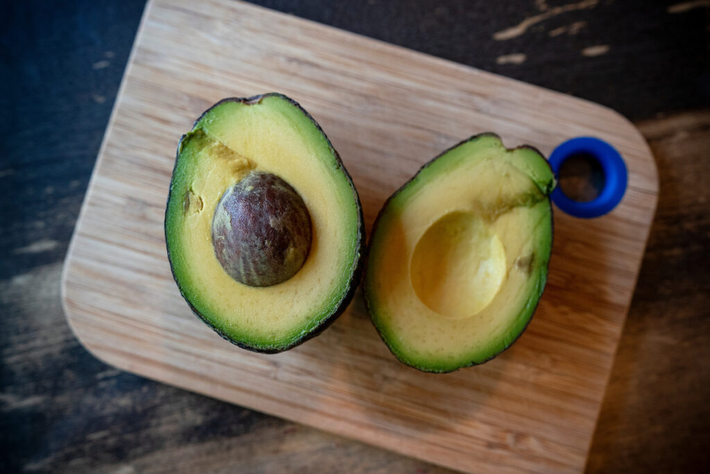 Two halves of an avocado on a cutting board