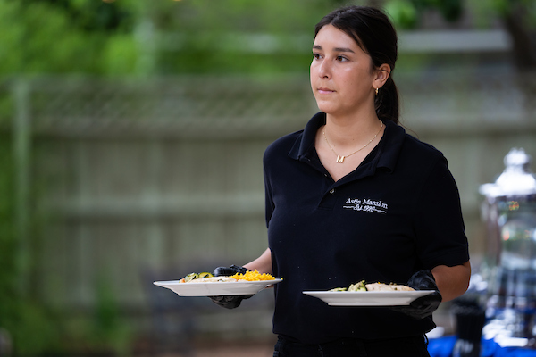A woman is serving food at an event.