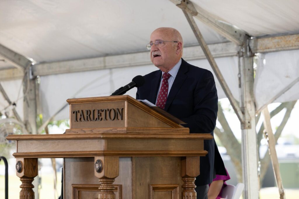 A man, Jeffrey W. Savell, Ph.D., speaks behind a podium that has the word Tarleton on the front of it. 