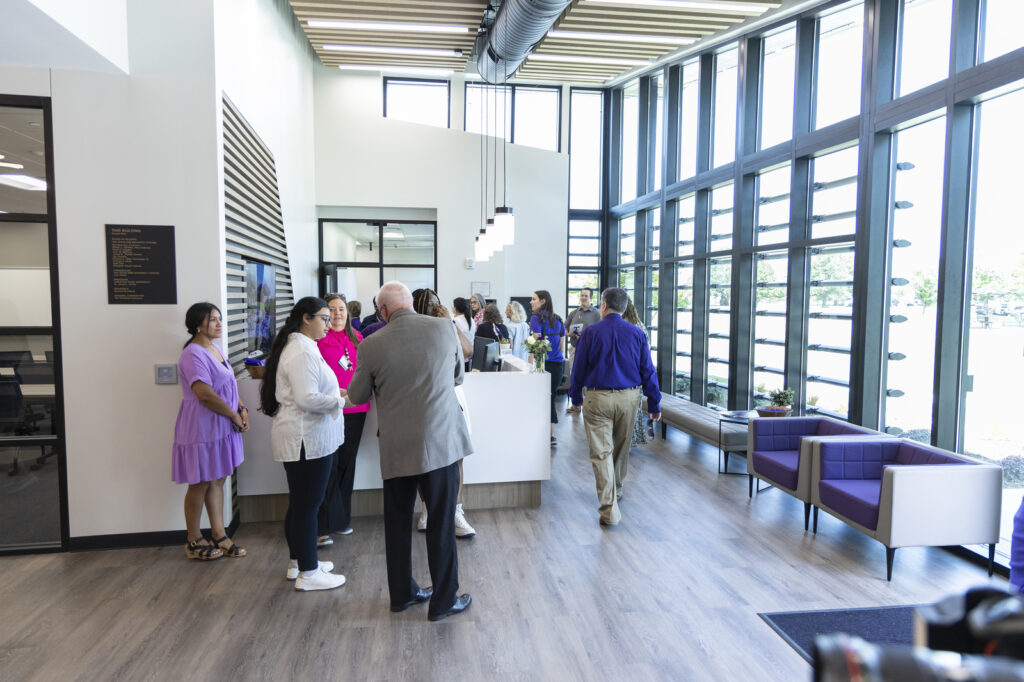 People in a large modern hall with floor-to-ceiling windows