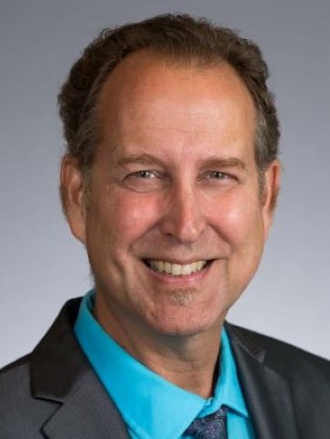 A headshot of Robert Brueggerhoff, radio host of Garden Success. He wears a bright blue shirt and dark jacket and tie