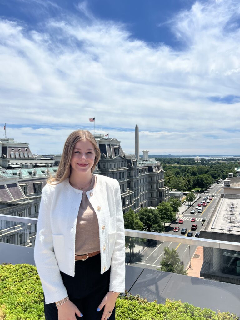 Zoë Meeks, who is completing an internship at the National Cotton Council, stands in a white blazer on a rooftop overlooking Washington, D.C.