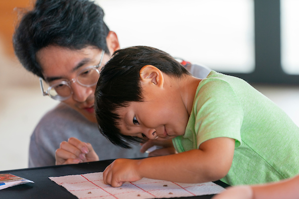 Man in glasses and little boy in green shirt working on a project together