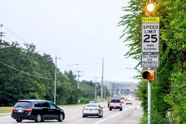 School zone with speed limit sign and vehicles driving through 