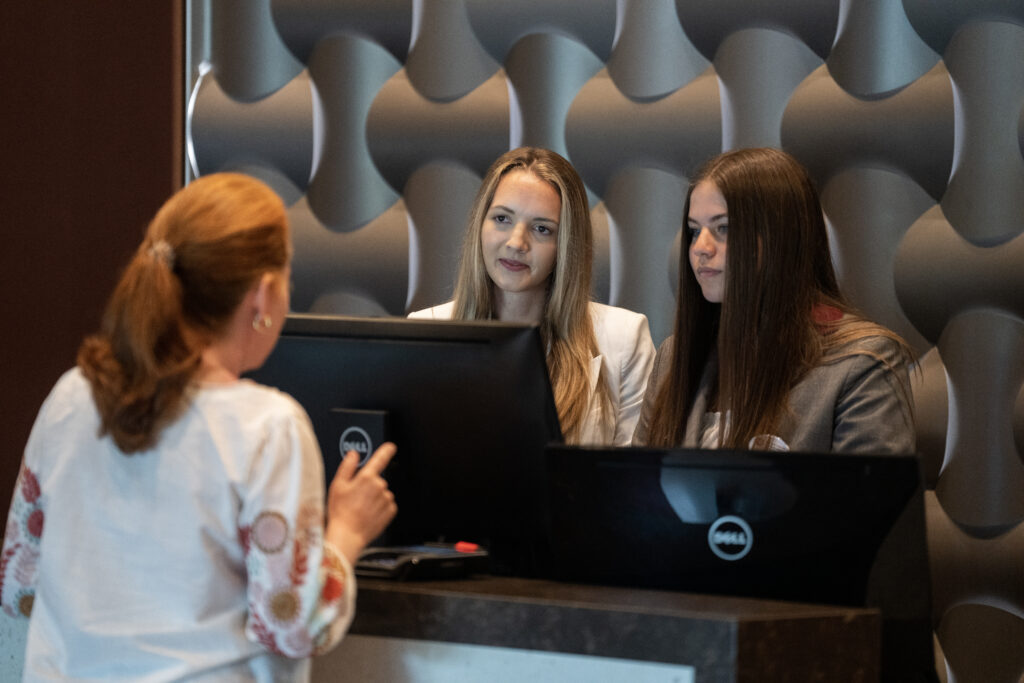 Students behind the front desk at the Texas A&M Hotel and Confernece Center in the Texas A&M campus