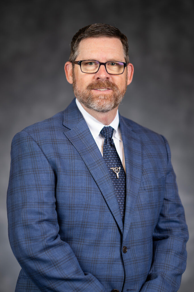 A smiling man in a glasses and a blue suit and tie, Andy Herring, Ph.D., associate head in the Department of Animal Science