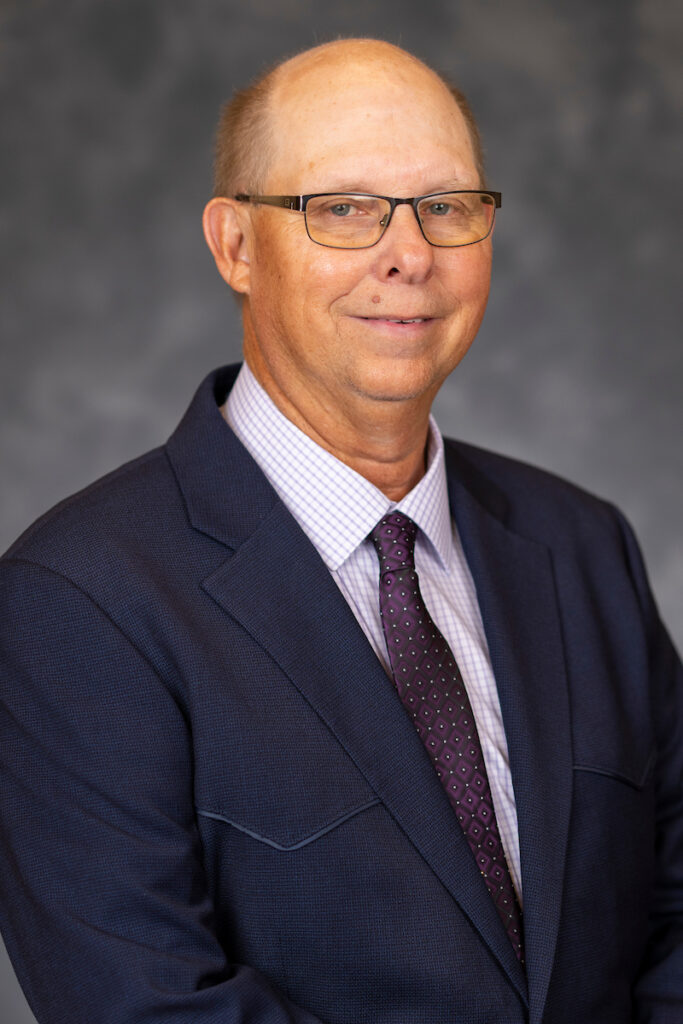 A smiling man in glasses and a dark blue suit