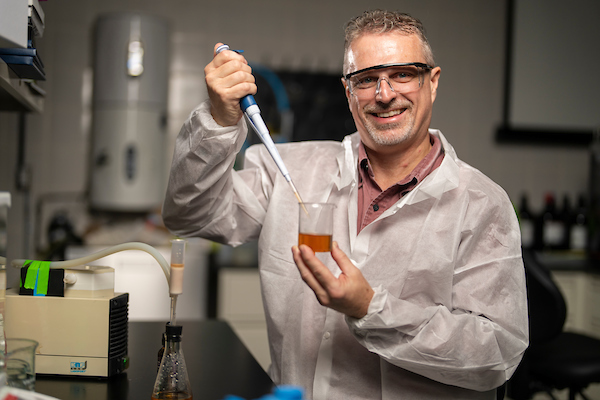 Stephen Talcott, Ph.D. in white lab coat holding beaker as he conducts research  