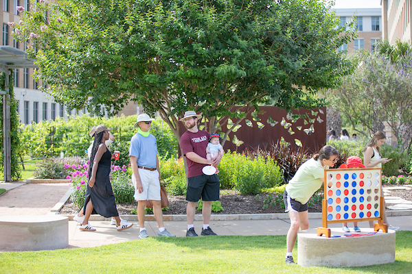 Adults and youth outdoors playing games and walking through The Gardens at Texas A&M