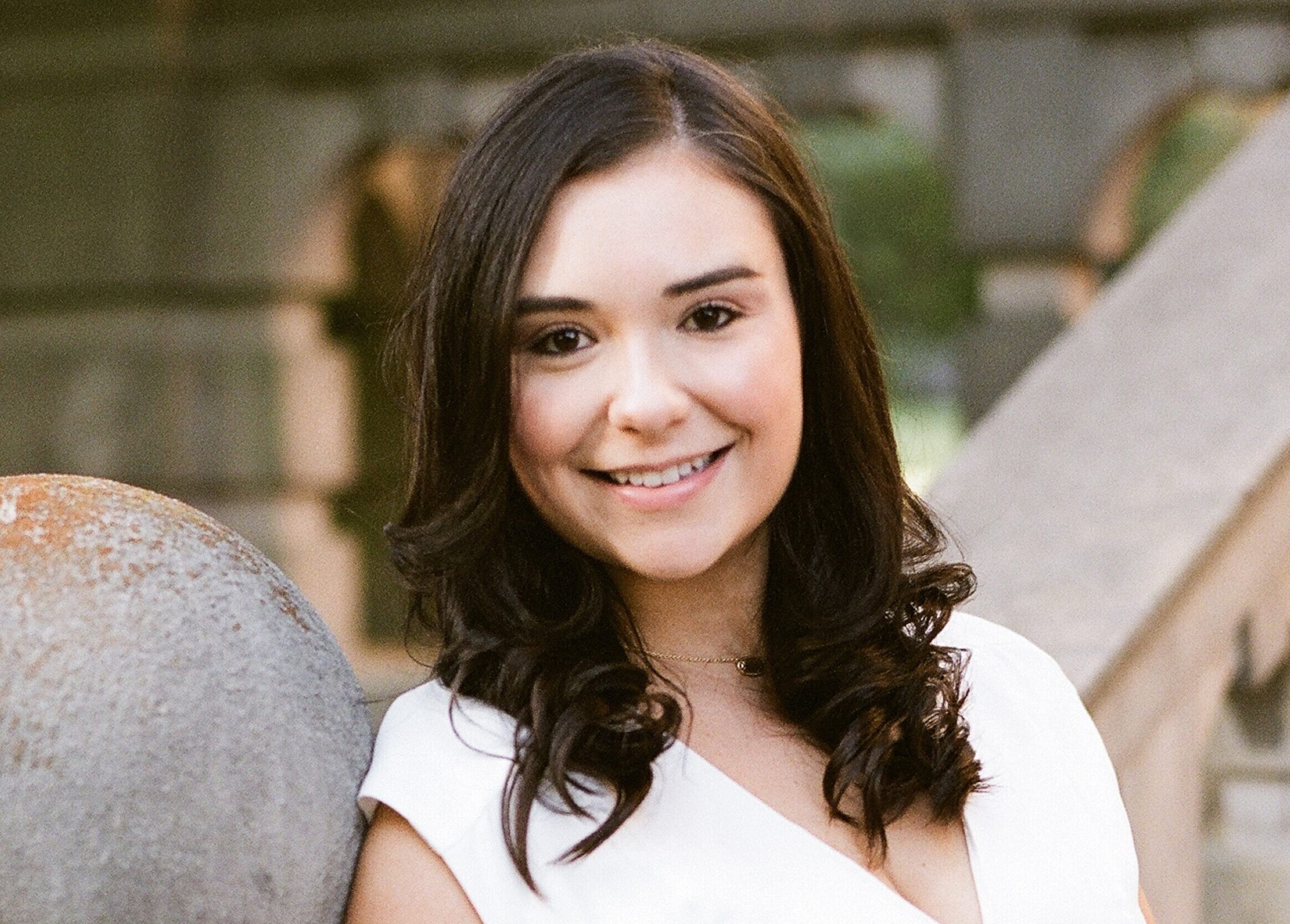 Woman with brown hair and white shirt smiling at camera.